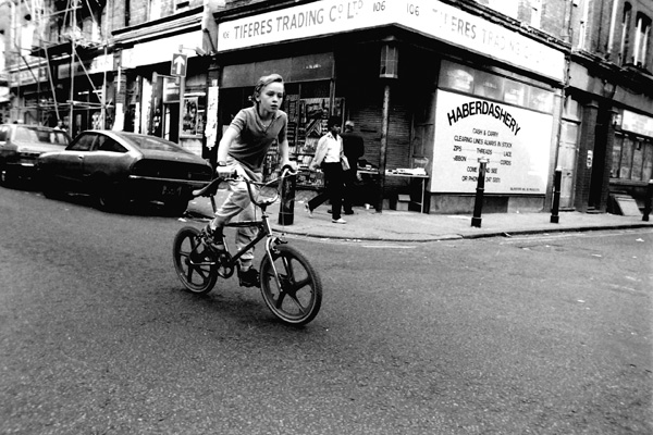 Boy riding a bike on Brick Lane, 1983