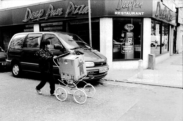 Boy carrying a box on the chassis of an old pram, Whitechapel Rd 1988