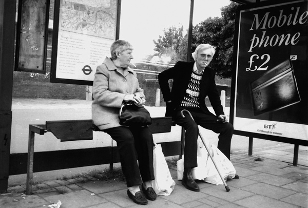 Two people wait for the arrival of a bus, Commercial Road 1990