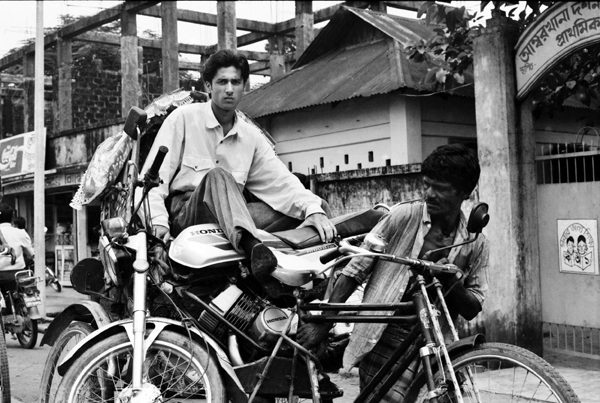 Rickshaw driver with motor bike and passenger. Dhaka, Bangladesh 1991