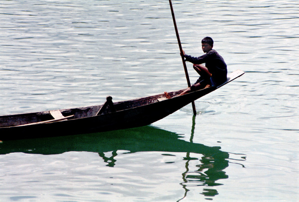 Boy steering a boat. Bangladesh 1996