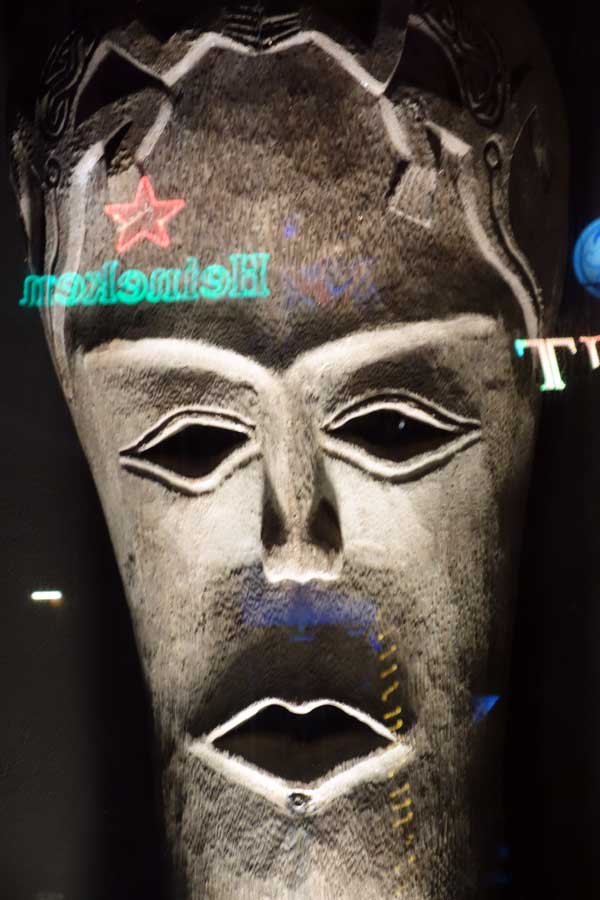 Tribal mask with advertising reflected on glass, Penang Malasia 2013