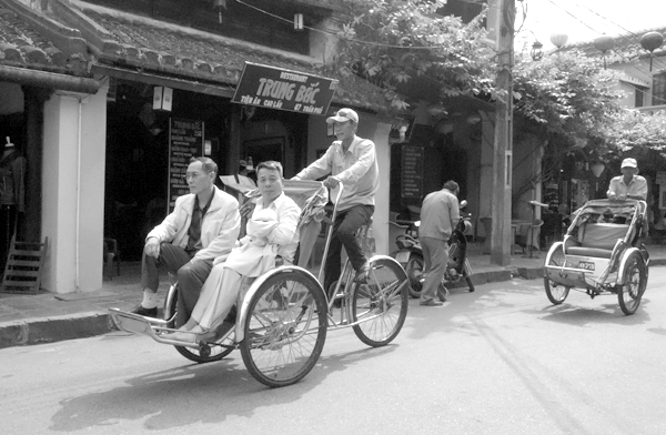 Rickshaw driver with passengers. Hoi An, Vietnam 2016.