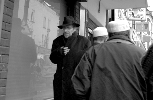 Pedestrians and reflections on Brick Lane. East London, January 2002.