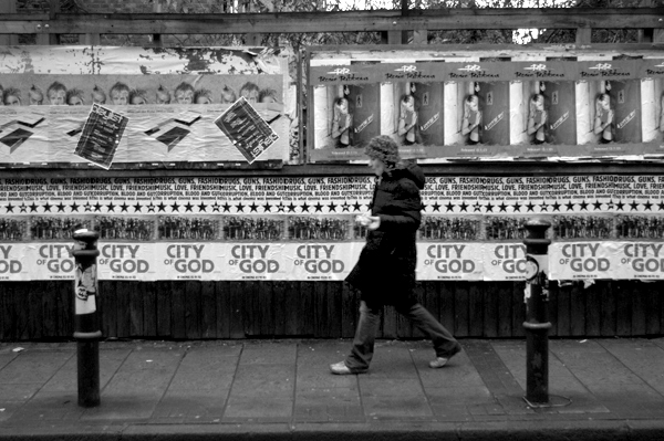 Walking past posters on Brick Lane. East London, January 2002.